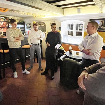 Personen stehen im Getränk in der Hand in einer Bar.