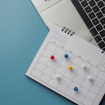 Kalender mit Pin-Nadeln liegt auf einem Laptop, Vogelperspektive