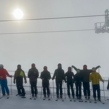 Gruppe von Skifahrer:innen nebeneinander auf Piste