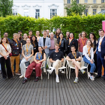 Gruppenbild einer Netzwerkveranstaltung, die Teilnehmer stehen im Freien. In der rechten Bildhälfte ist ein Roll-up mit der Aufschrift Junge Wirtschaft setzt Impulse