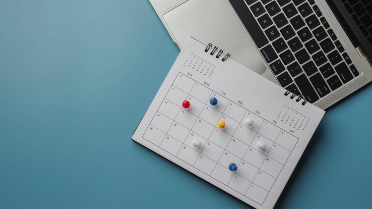 Kalender mit Pin-Nadeln liegt auf einem Laptop, Vogelperspektive