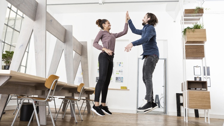 Zwei Personen springen in die Luft mit High-Five