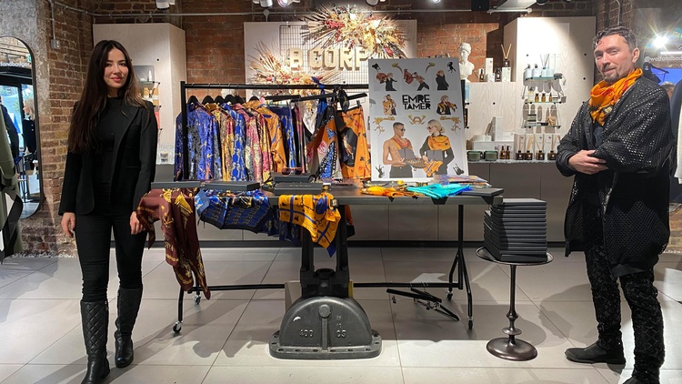 Frau und Mann stehen in Modegeschäft und schauen in die Kamera