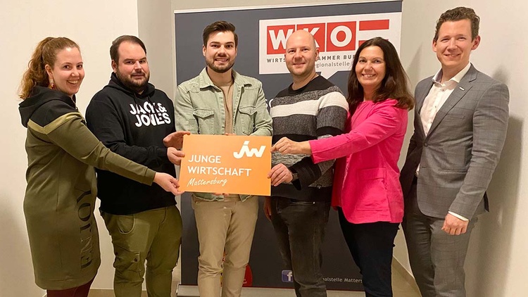 Gruppenbild mit sechs Menschen, die ein JW-Schild hochhalten