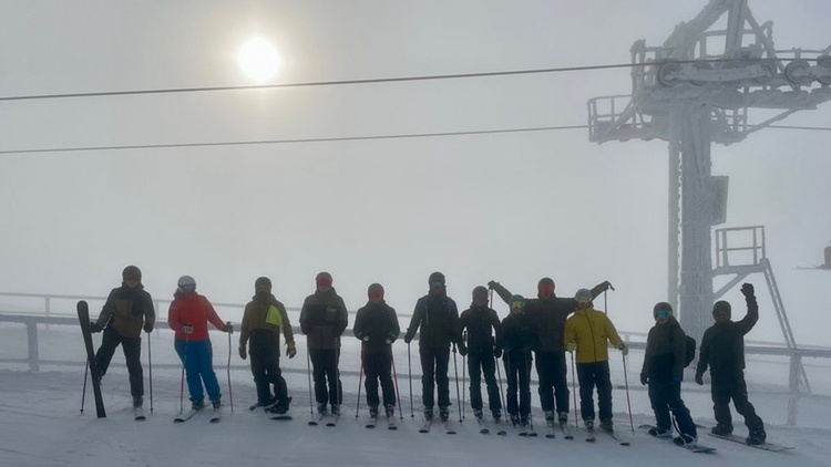 Gruppe von Skifahrer:innen nebeneinander auf Piste